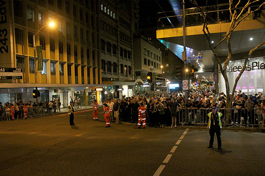 People wait for a street to be opened so they can cross. They were closed for hours at a time, and often no motorcades used them.