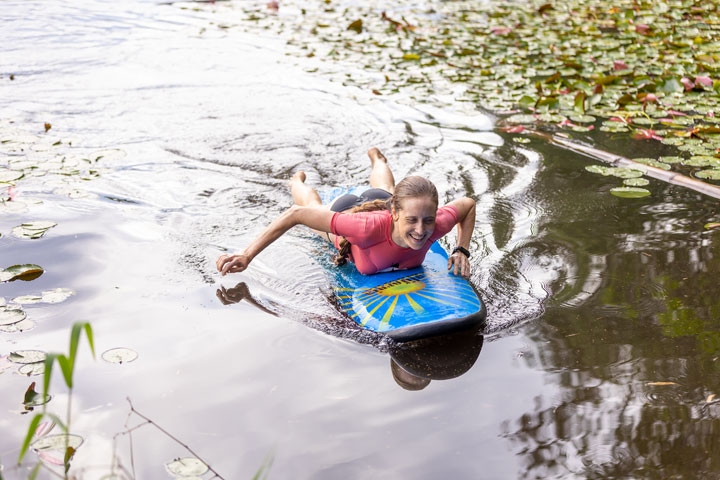 Bronwen trying to stand on a foam surfboard at Enoggera Reservoir