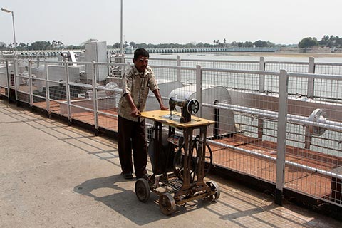 A man pushes a sewing machine across Kallanai Dam