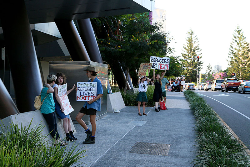 People hold signs along the side of the road