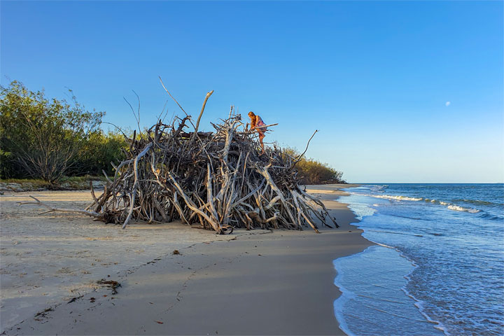 Bronwen climbing on a driftwood hut, Woody Bay, Bribie Island