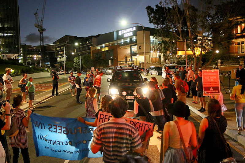 Protestors stop a police car and demand to search it