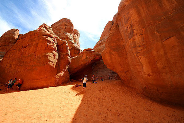 All the children were hiding in a sandy playground surrounded by rock walls, entered through a tunnel