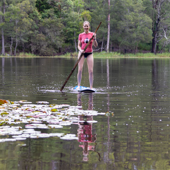 Bronwen trying to stand on a foam surfboard at Enoggera Reservoir