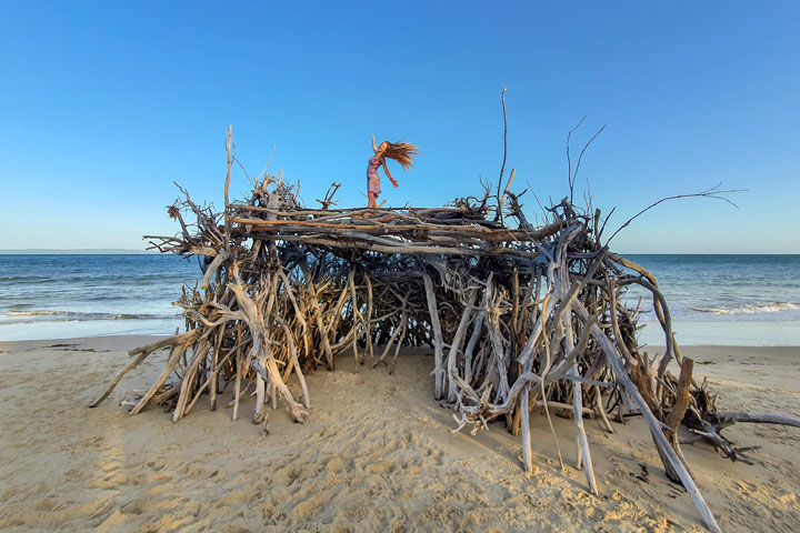 Bronwen climbing on a driftwood hut, Woody Bay, Bribie Island