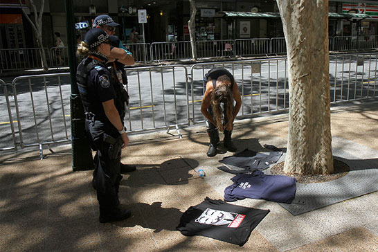 Police make a man remove his boots, presumably so they can walk a mile in them