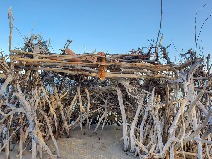 Bronwen climbing on a driftwood hut, Woody Bay, Bribie Island