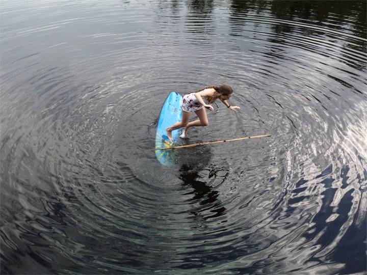 Bronwen trying to stand on a foam surfboard at Enoggera Reservoir