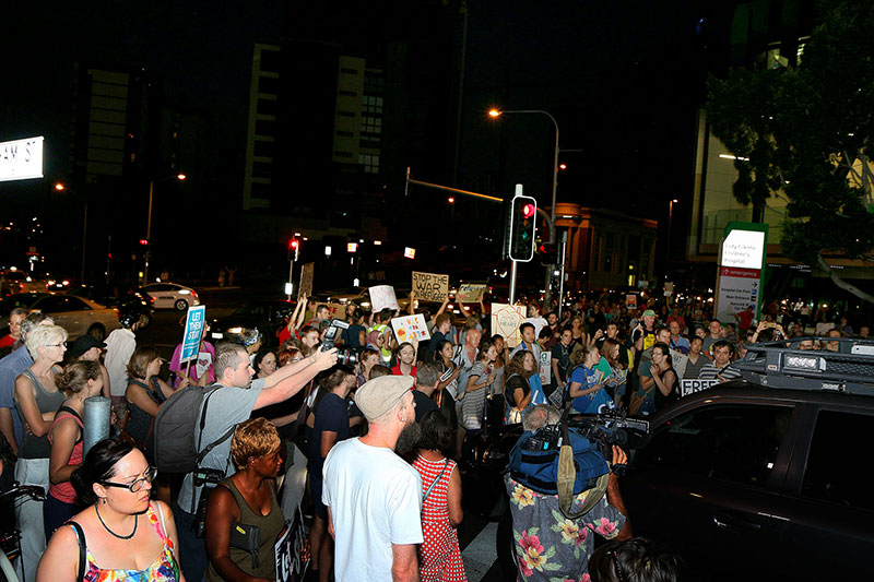 Protestors prevent a police car from passing