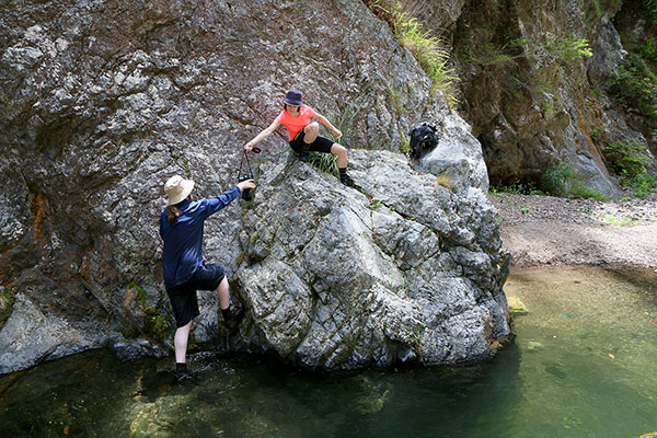 Bronwen & Maz passing camera gear over a rock