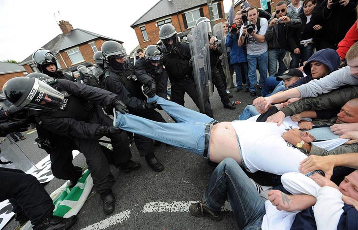 Police & Protesters help fat man remove pants