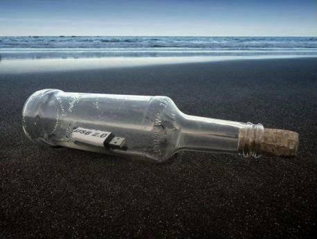 A USB stick in a bottle lying on the beach.