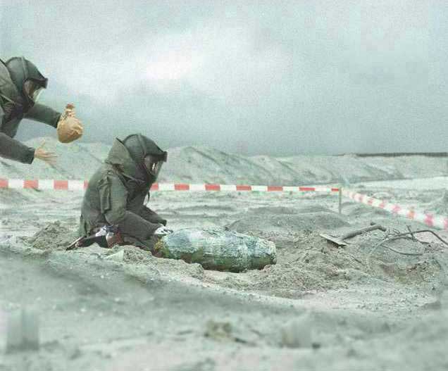 Man defusing bomb while man behind prepares to explode a brown paper bag as a joke