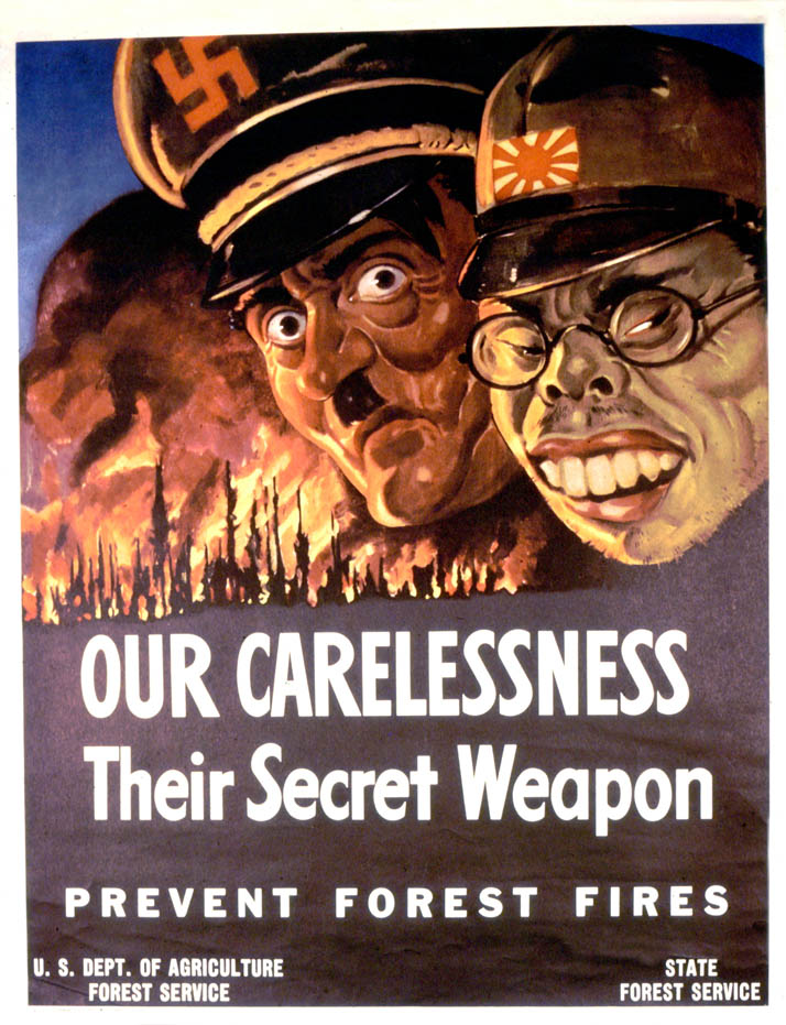 Caricatured faces of Hitler and Tojo look on as a forest fire rages